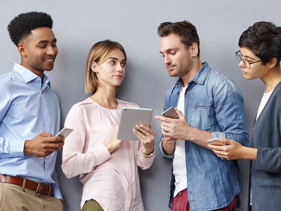 A group of people engrossed in their smartphones and tablets, illustrating the overstimulation and technological addiction of modern life