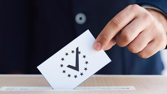 A close-up of a man casting his vote, placing a ballot into the ballot box
