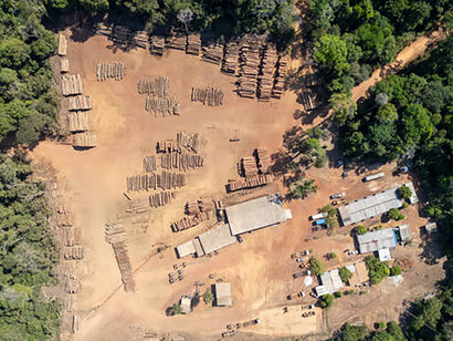 Aerial view of a log storage yard amidst deforested areas in the tropical rainforests of Malaysia