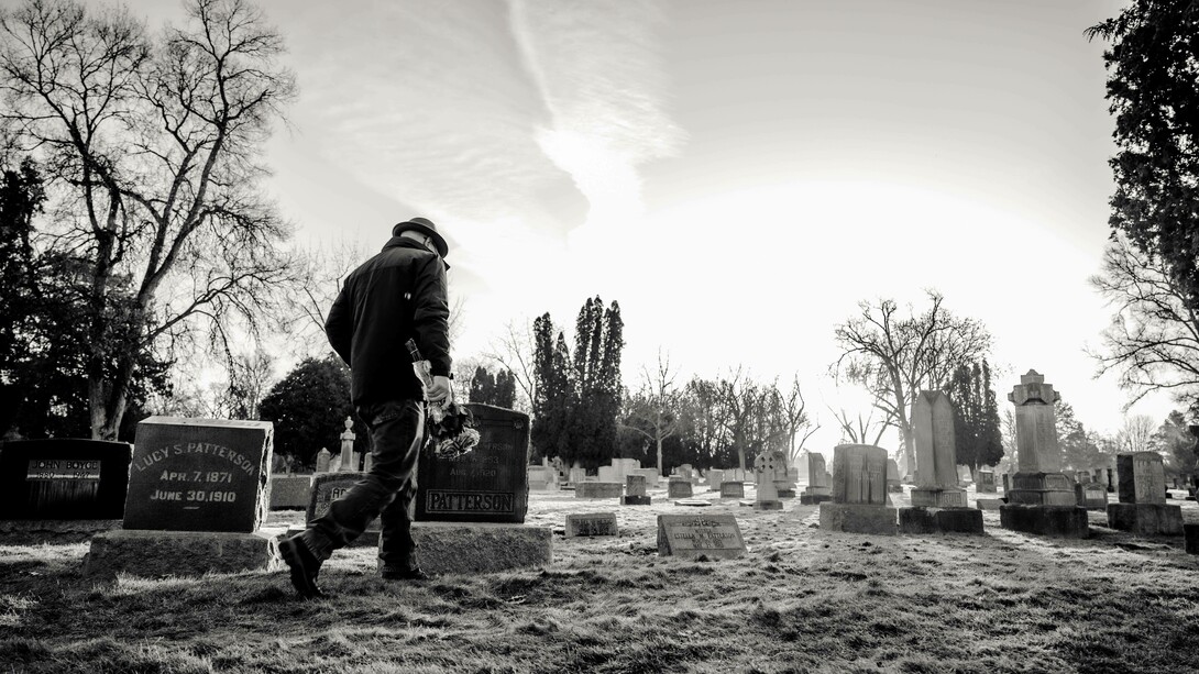 A person walking in a cemetery where the dead are buried but remembered 