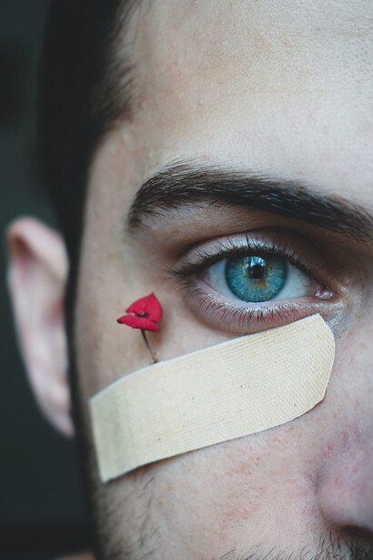 Man carrying a flower next to a first aid band under his eye, depicting domestic violence