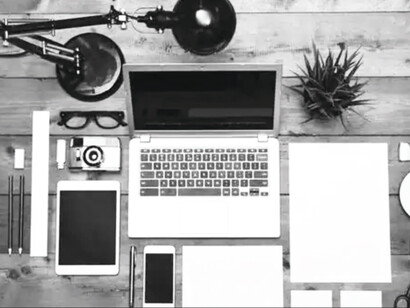 A person's workspace, full of digital devices and computer