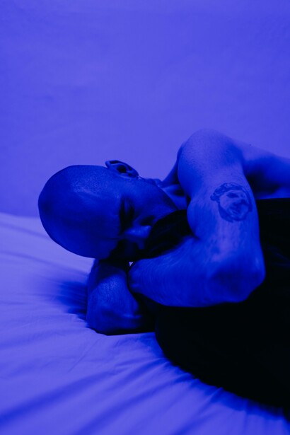 Homem sem camisa em quarto iluminado azul