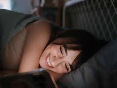 A woman lies awake at night, absorbed in her phone, illustrating the pull of social media addiction