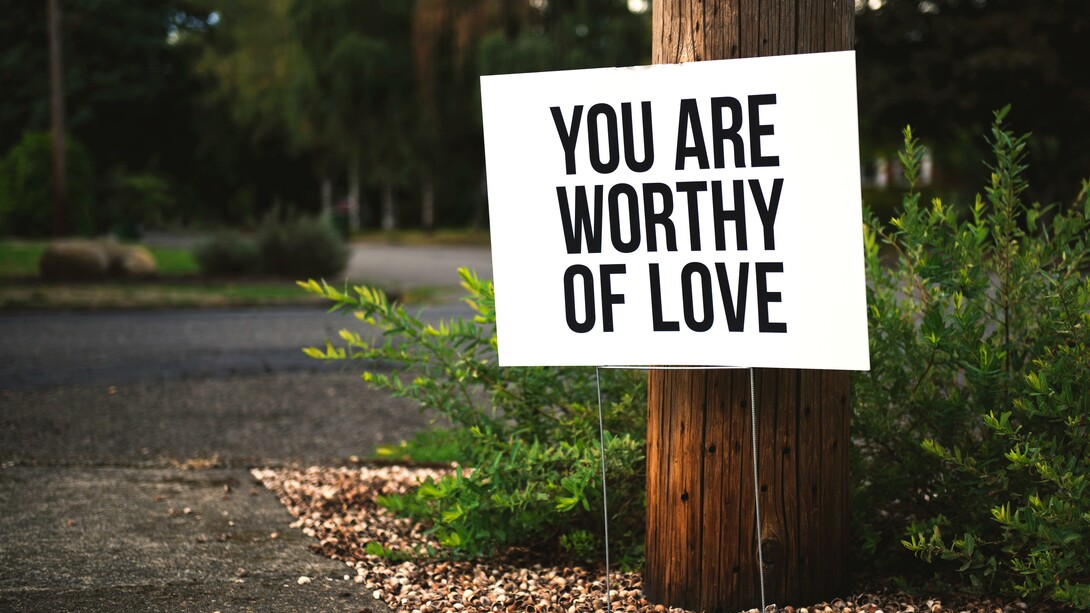 Love yourself. A reminder in the forest to practice self-love, that reads "You are worthy of love""