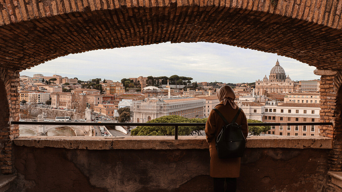 Mujer observa el movimiento cotidiano de la ciudad por un balcón en Roma, Italia