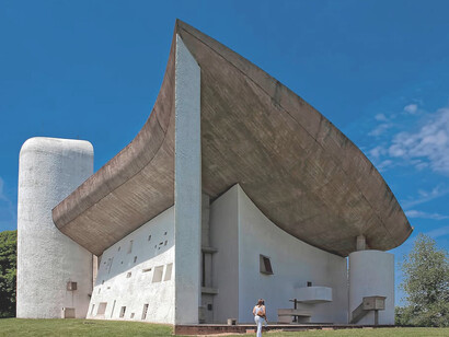 The asymmetrical roof of Notre Dame du Haut evokes a sense of warmth and intimacy, offering a unique spiritual experience, Ronchamp, France