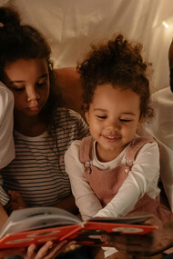 Família brasileira interracial desfrutando da leitura de um livro físico juntos