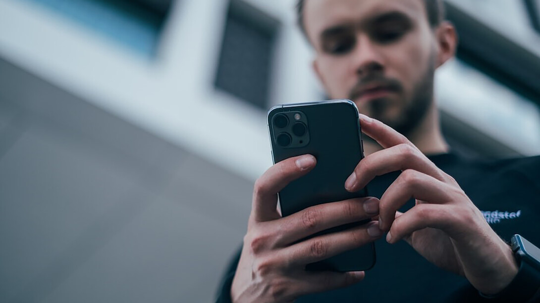 Man wearing black sweater using smartphone