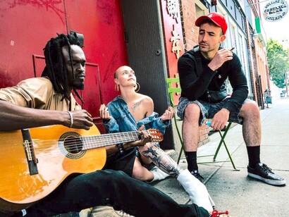 Homem e mulher sentados na rua tocando guitarra