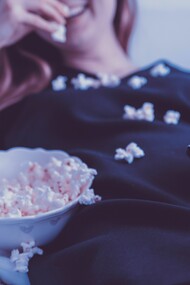 Woman watches tv with popcorn