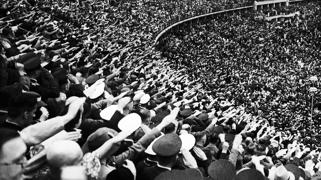 Una multitud en un estadio alemán hacen el saludo típico nazi (nacionalsocialista)
