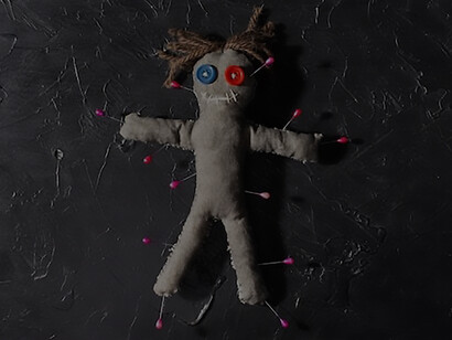 An overhead perspective captures a voodoo doll adorned with pins