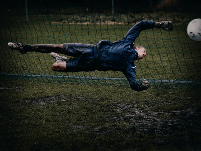 Portero se tira sobre el césped embarrado para evitar un gol