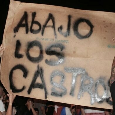 Manifestantes en Miami, Estados Unidos, sostienen un cartel que dice "Abajo los Castro", durante las protestas en 2021