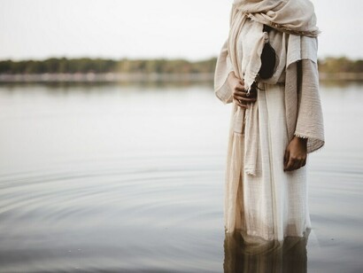 A figure in a biblical robe walks gracefully across the water