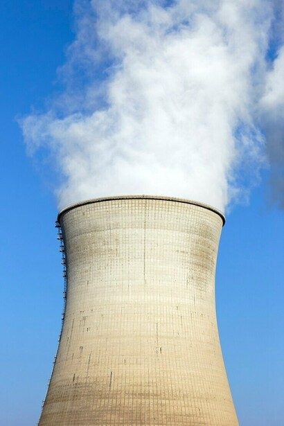 A vibrant summer landscape showcasing the smokestacks of a nuclear power plant 