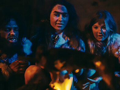 Experience the primal scene of Neanderthal and Homo sapiens families cooking and feasting on animal meat around a bonfire in a cave, embodying the ancient traditions of hunter-gatherer tribes