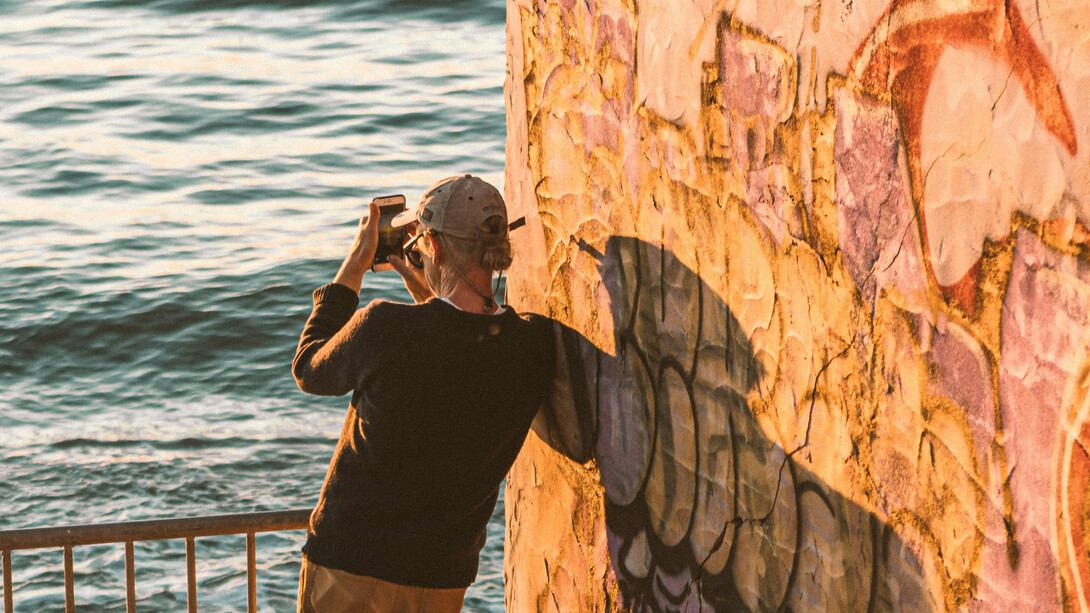Homem se concentra para tirar foto de paisagem. Viver no presente é uma jornada de autodescoberta que nos leva a experienciar a vida com total intensidade