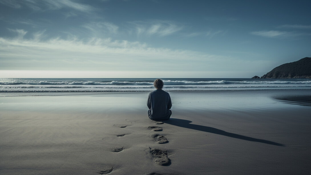 A solitary figure sitting by the vast sea, representing the quiet ache of emotional isolation