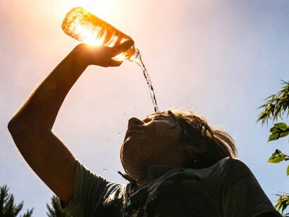 A woman refreshes herself with cold water while coping with the intense summer heat