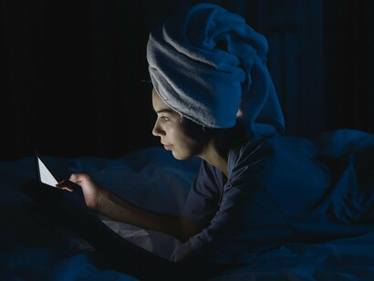 A woman scrolling on her phone at bedtime, symbolising how short-form content disrupts the brain’s natural wind-down process