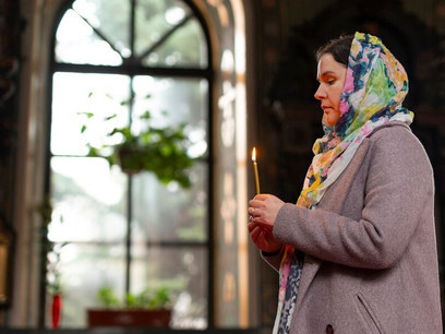 A woman praying in church with a candle, seeking inner strength, guidance, and wisdom