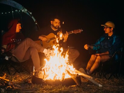 A quiet evening of music and conversation around a fire, symbolising traditions that gain meaning through shared presence instead of public visibility