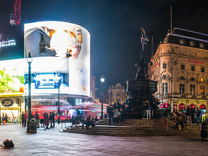 Crowds gather around the iconic Eros statue beneath the illuminated billboards of Piccadilly Circus in central London, UK