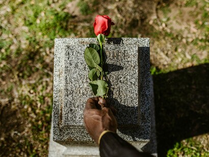 Pessoa deixa flor em lápide. Sem a compreensão ampliada da energia da morte, isto a que chamo de revolução, a tranquila aceitação dos fins, sem medo, sem culpa, sem dor, sem nada, apenas a consciência plena da vida que está na morte; não é possível termos acesso também a energia daquilo que faz nascer