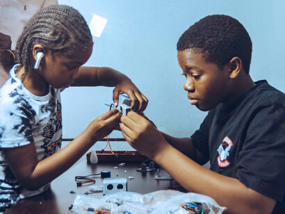 Two students carefully assembling electronic components during a tech class in Accra, symbolising education that moves beyond theory into practical skill-building