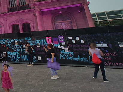 El Palacio de Gobierno barricado por murallas,  se iluminó en tonos morados y rosas por las manifestantes del 8M, 2024, Mexico