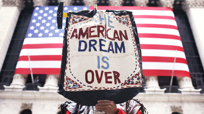 A protest sign of the American dream, in front of the American flag