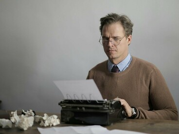 A writer confronting a blank page with uncertainty, reflecting the pressure to turn thoughts into meaning