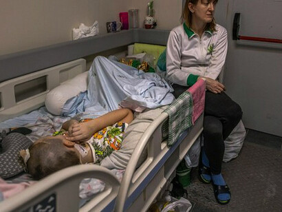 A sick child in a Ukrainian hospital assisted by his mother