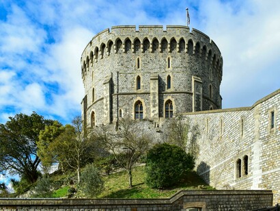 View of the Round Tower at Windsor Castle, England, UK, featuring the gray stone fortress topped with the royal flag beneath a clear blue sky