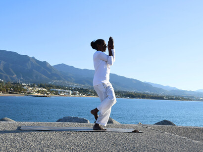 A yoga practitioner doing a pose beside the sea, representing inner balance amidst life’s changing situations