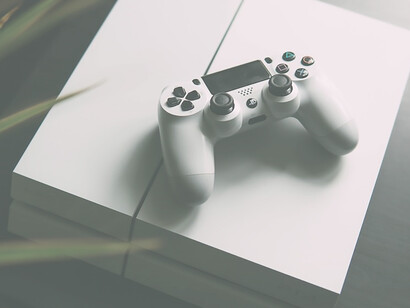 Selective focus photography of white Sony PS4 console with wireless controller