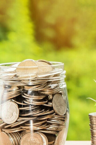 Jar of coins on a table representing cost of doing anything
