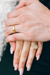 A close-up of a newly married couple’s clasped hands, representing the fragile beginning of a lifelong partnership