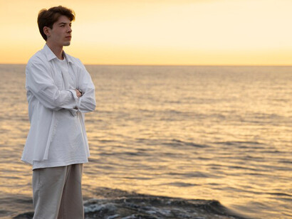 A serene woman practices mindfulness as she sits on a beach, embracing the stillness and quiet moments of nature around her