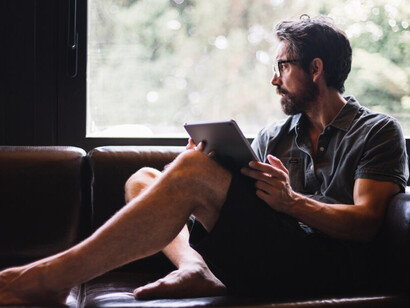 A freelancer working on a tablet, gazing out the window, enjoying the flexibility of his work routine
