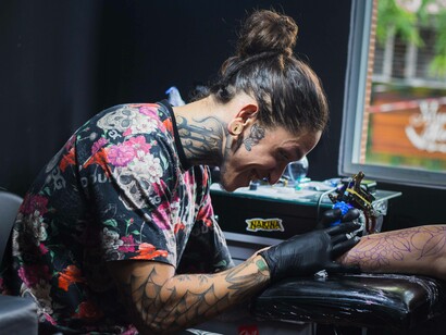 A tattoo artist in the middle of work while also following his soul-aligned business