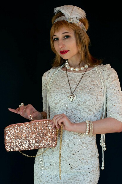 Nenhum look dos anos 1920 estava completo sem acessórios cuidadosamente coordenados. A cabeça era o ponto focal: o chapéu cloche, criado por Caroline Reboux, tornara-se quase uma extensão da silhueta. Moldado junto à cabeça, com aba estreita, realçava o corte bob e a nuca, uma área antes escondida, agora transformada em símbolo de sensualidade discreta