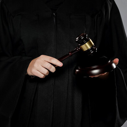 A male judge confidently posing with his gavel in a courtroom setting