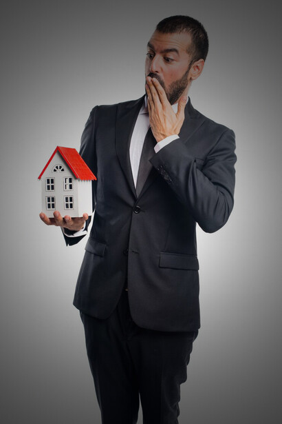 A real estate agent presenting a small house model, highlighting luxury real estate, modern living, and the scarcity of prime properties