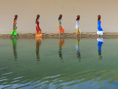 Mujeres siguiendo dunas a orillas del agua