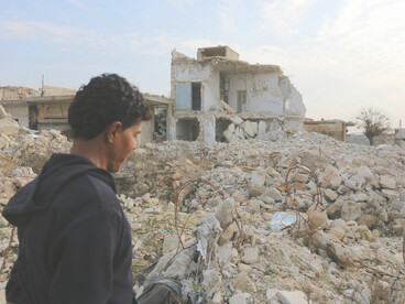 In Idlib, Idlib Governorate, Syria, a man surveys the war-torn ruins, highlighting the widespread devastation caused by conflict