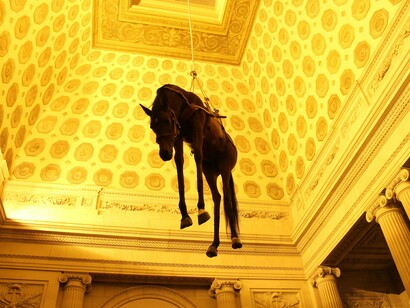 Cattelan faz uma crítica mordaz à ideia da obra de arte como um troféu. Ele também tem uma interpretação mais existencial: o desamparo da posição do cavalo e a impossibilidade de fuga podem ser um reflexo da condição humana