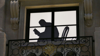 Ombra di un uomo alla finestra intento nella lettura di un libro